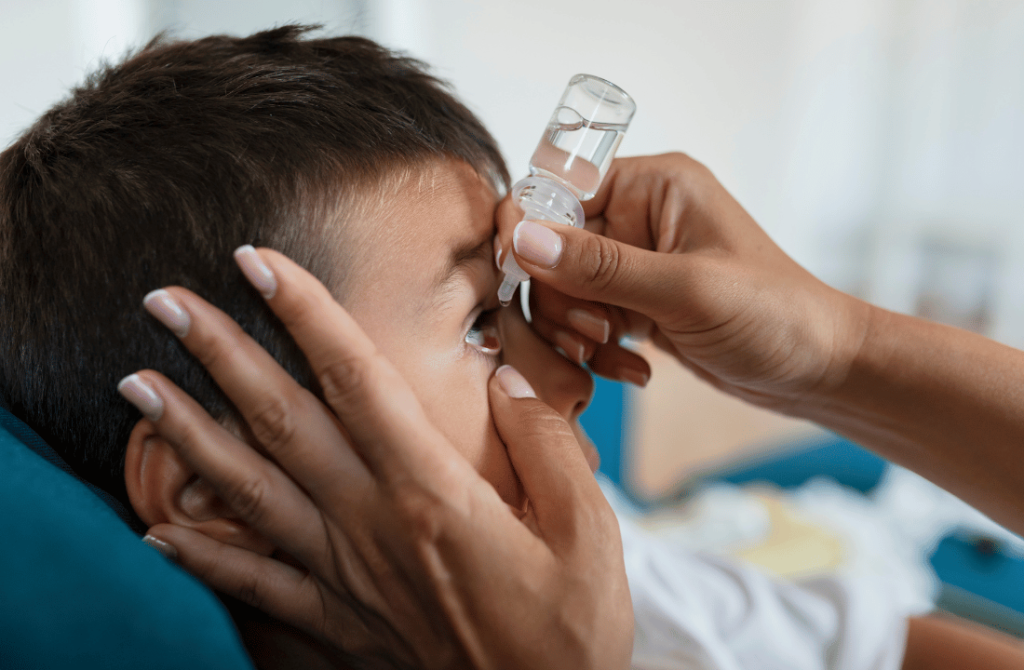 Close-up of a hand administering eye drops as part of pediatric eye care treatment.