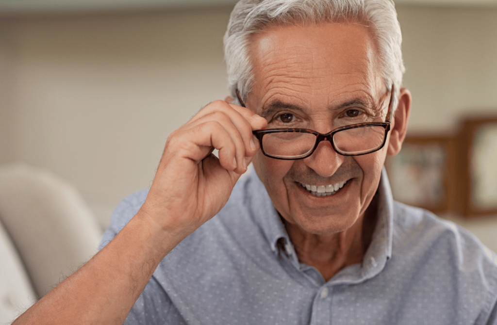 An elderly man wearing glasses, focusing on vision improvement after squint correction.