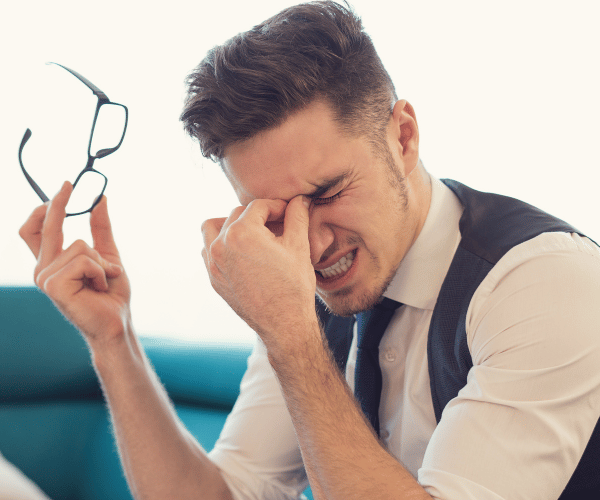 A man looking frustrated with glasses and contact lenses, considering an alternative like ICL lenses for a permanent vision solution.